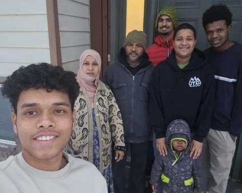 Picture of a family standing in front of their home. 