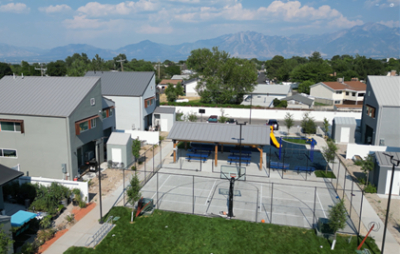 Picture of a basketball court, pavilion, and playground near some homes. 